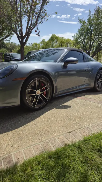 Graphite grey Porsche 911 Targa in profile after detailing, the paint mirroring the trees above it